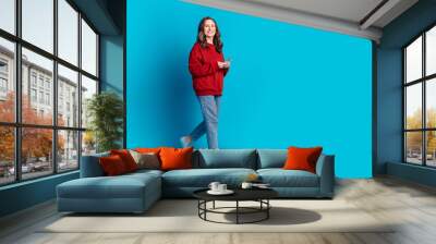 Full size photo of pretty aged lady walk use phone wear pullover isolated on blue color background Wall mural