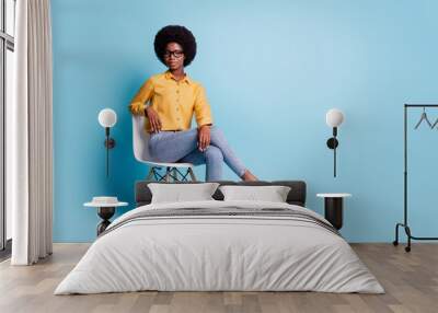 Full size photo of serious smart dark skin girl university college teacher young professor sit chair look good in camera wear stylish clothes isolated over pastel blue color background Wall mural