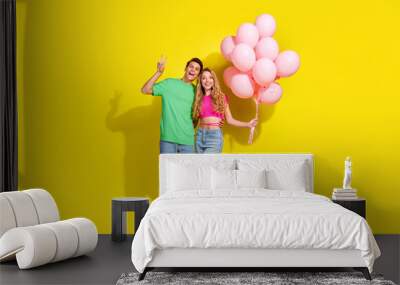 Full size photo of two nice young people show v-sign hold balloons isolated on bright yellow color background Wall mural