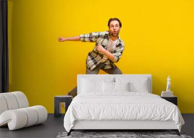 Full size photo of young excited man happy positive smile dance hip-hop music isolated over yellow color background Wall mural