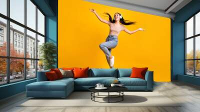 Full size photo of young happy crazy smiling cheerful girl dancing in headphones with flying hair isolated on yellow color background Wall mural