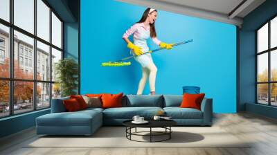 Full size profile photo of attractive funny lady house wife good mood hold mop like cleaning floor wear headband long dotted apron pink shirt pants shoes isolated blue color background Wall mural