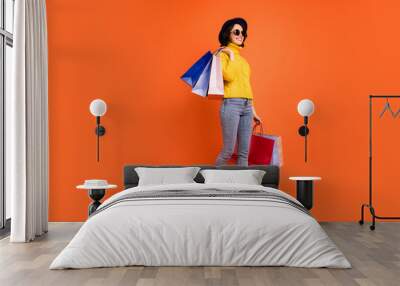 Fulll length body size photo of kind rejoicing overjoyed girl customer who just went out of shopping mall while isolated with orange background Wall mural