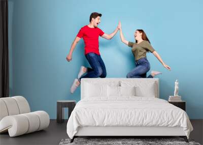 Great job. Full length profile side photo of cheerful two romantic people jump give highfive celebrate victory wear modern t-shirt denim jeans sneakers isolated blue color background Wall mural