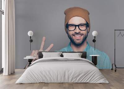 Handsome cheerful man  in hat and glasses showing v-sign Wall mural