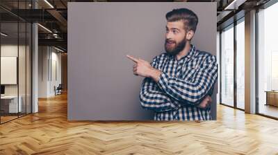 Handsome smiling bearded man showing direction with finger Wall mural