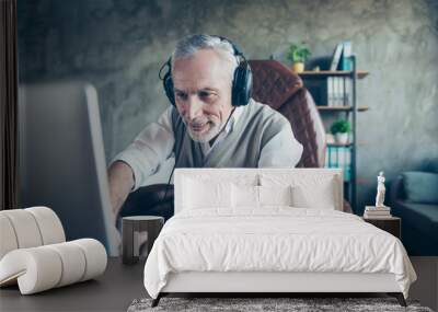 Happy cheerful delightful joyful funny employer is using his updated computer for playing games and listening to music via headphones Wall mural