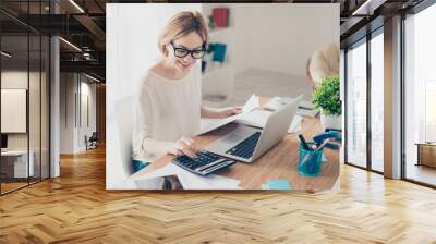 Happy cute  pretty accountant working with computer and calculator Wall mural