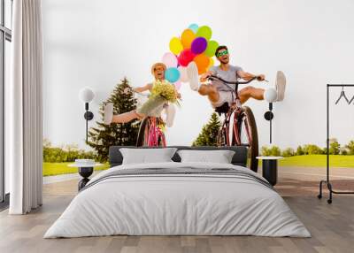 Happy funny young couple riding on bicycle with raised legs Wall mural