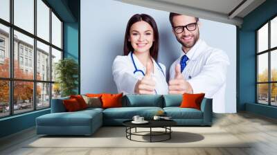 Happy medic workers. Portrait of two doctors in white coats and glasses showing thumb-up against white background Wall mural