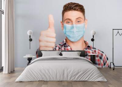 Happy positive young guy showing thumb up wear medical safety mask on face, stop pandemic corona virus prevention protection concept 2020 covid19 Wall mural