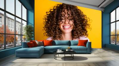 Headshot of laughing cheerful girl with curly hairstyle wearing t-shirt white toothy smile isolated on bright yellow color background Wall mural