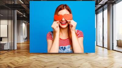 I love you! Close up studio photo portrait of cute lovely pretty with beaming toothy smile girl covering eyes with small little postcards in shape on heart isolated bright vivid background Wall mural