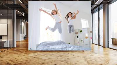 Low angle photo of cheerful kids jumping bed have free time raise hands feel content room indoors apartment Wall mural