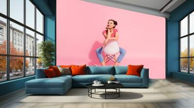 Nice-looking attractive glamorous magnificent lovely shine cheerful cheery girl wearing striped tshirt jeans sitting on chair having free time isolated over pink pastel background Wall mural