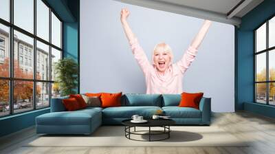 Old blonde glad excited lady smiling, laughing, raising hands up, opened mouth, over grey background, copy space Wall mural