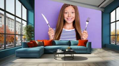 Photo of adorable hungry girl straight hairdo wear striped t-shirt hold spoon knife delicious food isolated on purple color background Wall mural