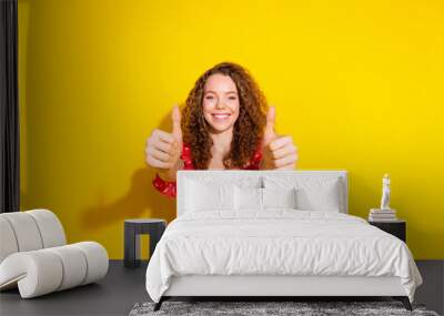 Photo of adorable lovely girl wear red top showing two thumbs up empty space isolated yellow color background Wall mural