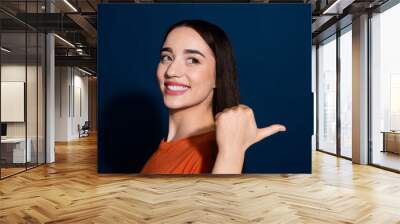 Photo of adorable pretty cute woman wear stylish orange clothes introduce empty space isolated on dark blue color background Wall mural