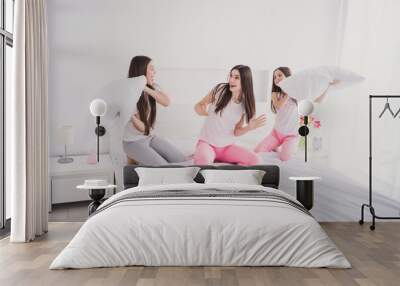 Photo of adorable sweet three sisters sleepwear sitting bed pillow fighting smiling inside indoors home room Wall mural