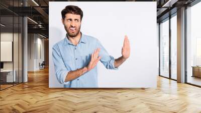 Photo of amazing multiethnic guy looking empty space with disgust stop with arms movement to him wear casual denim shirt isolated white color background Wall mural