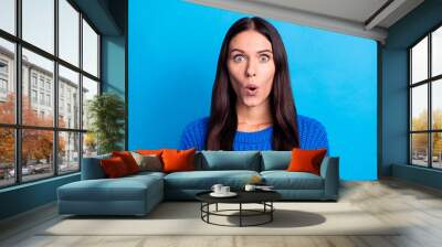 Photo of astonished young woman wear knitted blue sweater shocked discount isolated on blue color background Wall mural