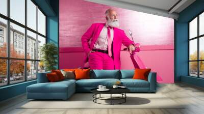 Photo of attractive charming mature grandfather macho stand motor bike posing look empty space pink color wall in interior wear blazer Wall mural