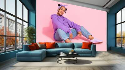 Photo of attractive cool afro woman wear purple hoodie buns sitting floor smiling isolated pink color background Wall mural