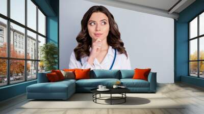 Photo of attractive family doc lady patients consultation virology clinic look side empty space interested hand on chin wear white lab coat stethoscope isolated grey color background Wall mural