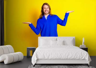 Photo of attractive positive man wear trendy clothes demonstrate empty space isolated on yellow color background Wall mural