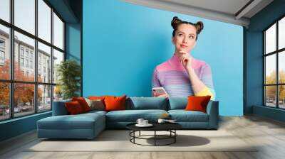 Photo of attractive teen lady two buns good mood freelancer hold telephone look up empty space dreamy writing post arm chin wear casual striped sweater isolated blue color background Wall mural