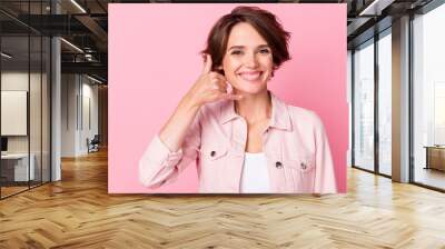 Photo of attractive young woman good mood make call me sign fingers isolated on pastel pink color background Wall mural