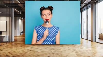 Photo of beautiful lady holding metal spoon in mouth look up empty space dreaming about tasty food wear dotted blouse shirt white isolated blue color background Wall mural