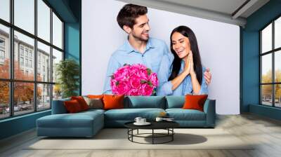 Photo of beautiful nice cute couple of two people girlfriend rejoicing with receiving bouquet of fuchsia flowers and boyfriend hugging her from back in jeans denim isolated grey color background Wall mural