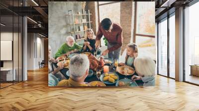 Photo of big family sit feast meals table around roasted turkey father guy making slice for little daughter hungry relatives waiting evening party in living room indoors Wall mural