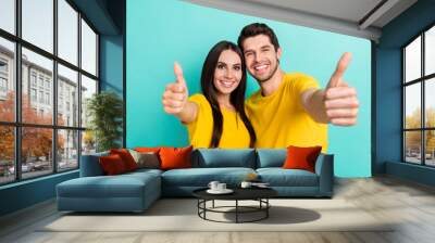 Photo of charming positive husband wife dressed yellow t-shirts cuddling showing you thumbs up isolated turquoise color background Wall mural