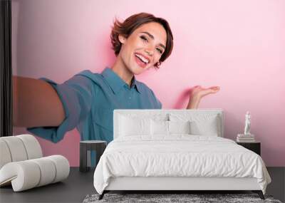 Photo of charming positive lady take selfie arm hold demonstrate empty space isolated on pink color background Wall mural