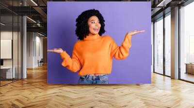 Photo of charming positive woman wear orange sweater showing arms scales empty space isolated violet color background Wall mural