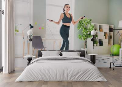 Photo of charming sexy young lady wear sport outfit smiling cardio training jumping rope indoors home house Wall mural