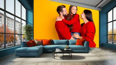 Photo of cheerful charming cute family with mommy and daddy embracing their daughter holding with hands wearing red jeans denim smiling toothily isolated vivid yellow color background Wall mural