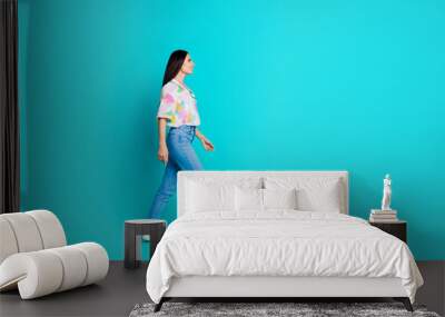 Photo of cheerful cute woman dressed summer trendy clothes looking empty space isolated on cyan color background Wall mural