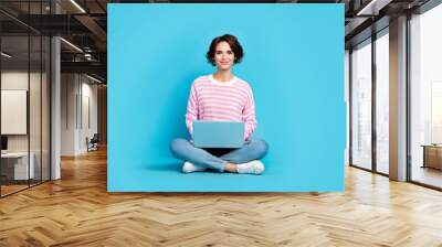 Photo of cheerful girl sitting floor browsing online working on new project document isolated on blue color background Wall mural