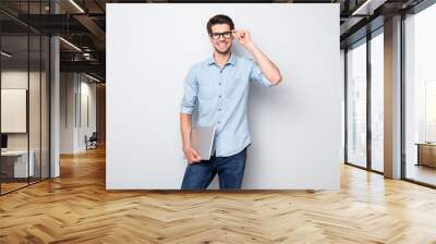 Photo of cheerful handsome attractive clever man smiling toothily holding laptop with hands showing his intelligence with style isolated over grey color background Wall mural