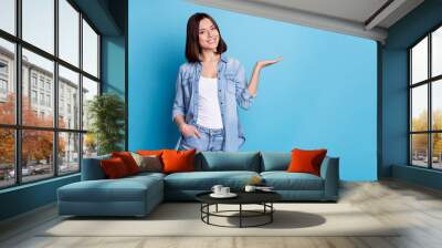 Photo of cheerful person arm palm hold demonstrate empty space isolated on blue color background Wall mural