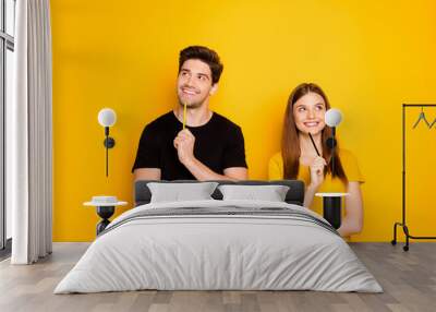 Photo of cheerful positive cute nice charming couple of two people pondering over surprise for each other isolated over vivid color background in black t-shirt Wall mural