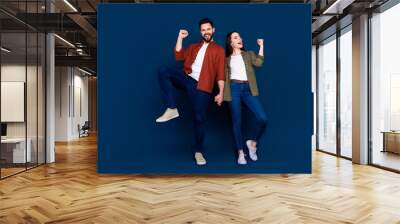 Photo of cheerful positive glad wife and husband wear stylish clothes yeah hooray sale isolated on dark blue color background Wall mural