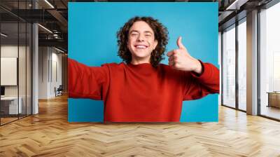 Photo of cheerful positive guy dressed red pullover recording video showing thumb up isolated blue color background Wall mural