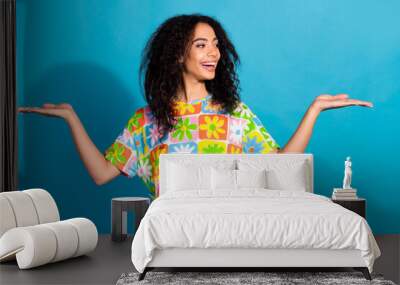 Photo of cheerful pretty lady dressed flower print t-shirt showing arms scales empty space isolated blue color background Wall mural