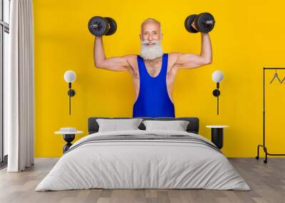 Photo of cheerful sportive aged person hands hold lifting dumbbells isolated on yellow color background Wall mural