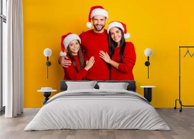 Photo of cute affectionate adorable family smiling toothily hugging each other wearing jeans denim santa cap headwear smiling toothily isolated over vivid color yellow background Wall mural